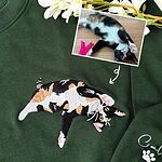 Forest green cat mom sweatshirt with a full-body calico cat embroidered from the photo shown above it, and the cat name with a paw print on the sleeve