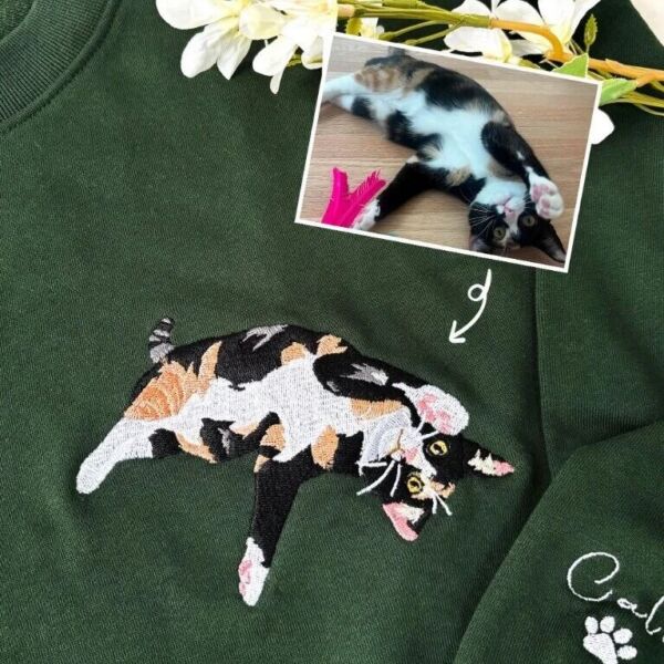 Forest green cat mom sweatshirt with a full-body calico cat embroidered from the photo shown above it, and the cat name with a paw print on the sleeve
