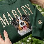 Detail of custom dog face embroidery and personalized Marley name on a green sweatshirt