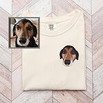 Custom embroidered black and tan dog portrait on an ivory T-shirt beside the original pet photo