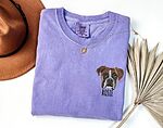 Custom embroidered Boxer dog face portrait and pet name Rosie on a purple sweatshirt flatlay with accessories