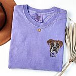 Custom embroidered Boxer dog face portrait and pet name Rosie on a purple sweatshirt flatlay with accessories