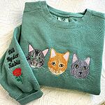 Sage green sweatshirt featuring 3 custom embroidered cat faces tabby orange and grey with sleeve embroidery of three pet names and red rose