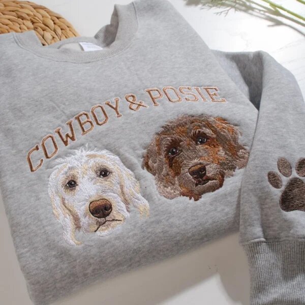 Detailed close-up of custom embroidered cream and brown doodle dog faces with Cowboy and Posie lettering and embroidered paw on sleeve cuff