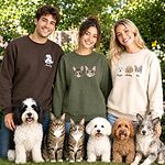 Three pet owners wearing custom embroidered portrait sweatshirts with dogs and cats outdoors