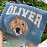 Blue custom pet portrait varsity sweatshirt embroidered with a dog face, Oliver name, and EST. 2023