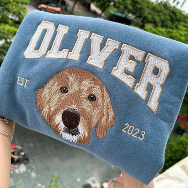 Blue custom pet portrait varsity sweatshirt embroidered with a dog face, Oliver name, and EST. 2023