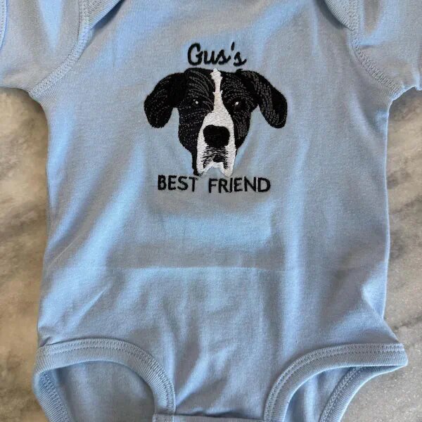 Blue baby bodysuit embroidered with a custom dog portrait and Gus's Best Friend text