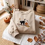 Cozy sand beige embroidered sweatshirt featuring a Halloween black cat on a witch broom with pumpkin, crescent moon, and autumn decor