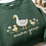 Close-up embroidery stitch detail showing white mother goose, two yellow goslings, daisies, and cursive mama goose lettering