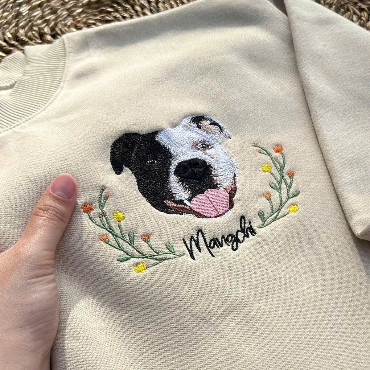 Personalized Dog Face Embroidered Sweatshirt Close-Up Personalized black and white dog face embroidery with pet name on a cream sweatshirt