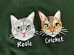 Two embroidered cat portraits of grey tabby named Rosie and brown tabby named Cricket with custom stitched names on dark green garment