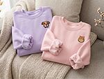Lavender and pink embroidered sweatshirts featuring custom dog and cat portraits