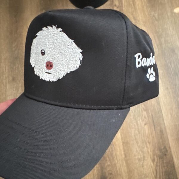 Customer photo of a black cap with a white embroidered dog portrait, side name and paw print