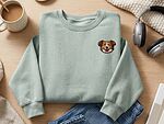 Sage green sweatshirt with a small custom embroidered dog portrait on the left chest