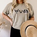 Model wearing a T-shirt embroidered with three dog portraits across the chest