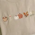 Extreme close-up macro view of dense high-sheen satin stitch embroidery showing pumpkin spice mug, dog, pumpkins, and fall leaves on sand fleece