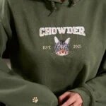 Model wearing a dark forest green custom embroidered cat portrait hoodie with arch text Chowder, EST 2021, and embroidered paw print on sleeve cuff