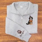 Sport grey quarter zip fleece pullover featuring embroidered Bernese Mountain Dog with jack-o-lantern bucket and sleeve personalization on warm wood tabletop