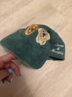Dark green washed baseball cap with two embroidered golden retriever dog faces on front and custom embroidered cursive names Turbo and Murphy on side panel