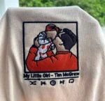 Sand colored embroidered photo shirt featuring a father kissing his baby with My Little Girl Tim McGraw song embroidery and music controls