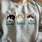 Heather grey crewneck sweatshirt featuring custom embroidered three cat faces side-by-side named Smidge, Tabitha, and Wolfie with green stitched lettering