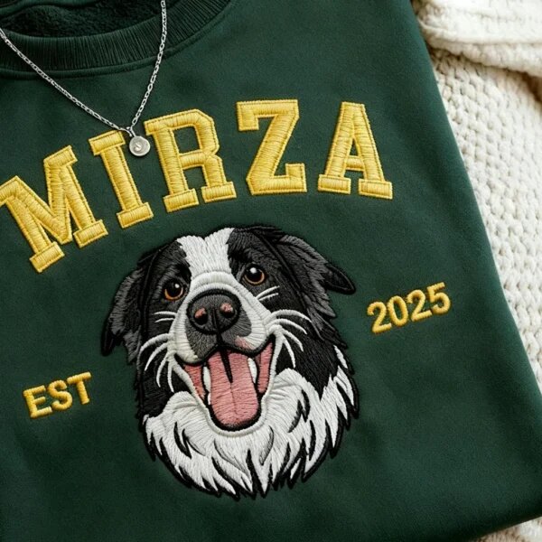 Detailed macro close-up of embroidered border collie dog face and yellow 3D satin stitch varsity lettering Mirza on dark green fleece