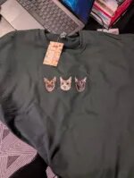 Customer photo review of forest green crewneck sweatshirt featuring three realistic embroidered pet faces with two German Shepherds and one cat