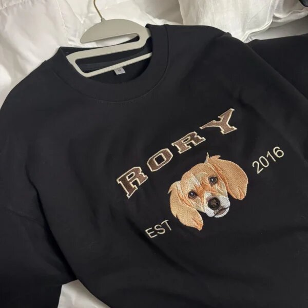 Black crewneck sweatshirt on a hanger, embroidered with a dog portrait, the name Rory and EST 2016