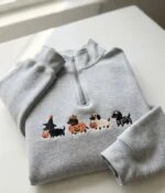 Heather grey quarter zip sweatshirt embroidered with playful Halloween dachshunds including witch, pumpkin, ghost, and skeleton pups