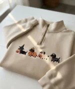 Warm sand beige quarter zip fleece pullover embroidered with four spooky Halloween dachshund dogs with pumpkin buckets in natural sunlight