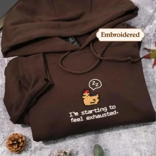 Espresso brown embroidered pullover hoodie displaying centered sleepy pixel chicken with sleep bubble and I'm starting to feel exhausted embroidery