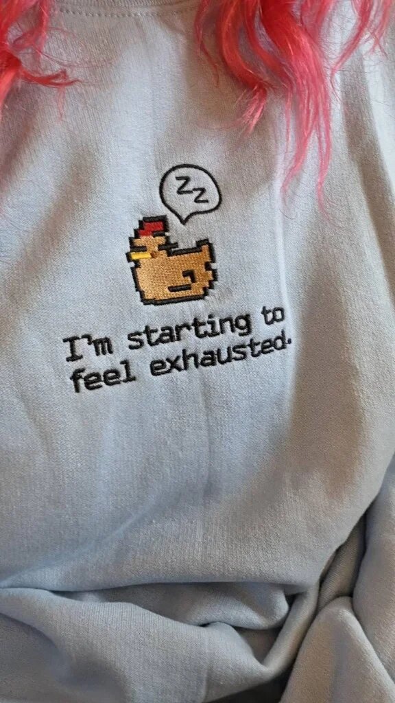 I'm Starting to Feel Exhausted Embroidered Sweatshirt – Light Blue Wearer Close-Up Close-up view of light blue embroidered crewneck sweatshirt worn with sleepy chicken and I'm starting to feel exhausted quote