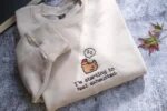 Sand cream embroidered crewneck sweatshirt with folded sleeve showcasing detailed pixel art chicken embroidery and clean typography