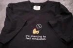 Classic black embroidered cotton t-shirt with detailed brown pixel chicken and I'm starting to feel exhausted quote across chest