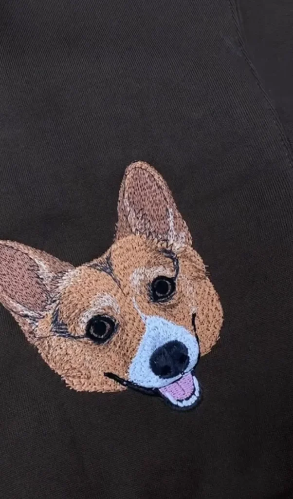Close view of thread details in a corgi portrait embroidered on a brown sweatshirt