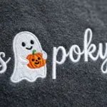 Close-up of the raised satin embroidery on the ghost icon and cursive lettering