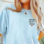Woman in a Chambray T-shirt embroidered with adopt don't shop in black stacked letters and a small red heart on the left chest