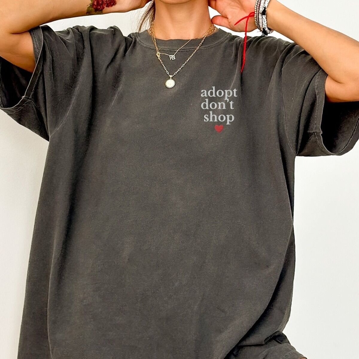 Adopt Don't Shop Shirt – Pepper Woman in an oversized Pepper T-shirt embroidered with adopt don't shop in white stacked letters and a red heart on the left chest