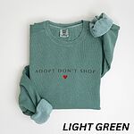 Light Green crewneck sweatshirt laid flat on white, embroidered with ADOPT DON'T SHOP in dark spaced capitals and a red heart