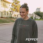 Woman on a city street in a Pepper crewneck sweatshirt embroidered with ADOPT DON'T SHOP in light capitals and a small red heart