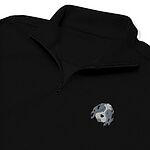 Close-up of a Black quarter zip collar and chest, embroidered with a blue merle aussiedoodle face with a white blaze and blue eyes on the left chest