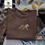 Dark Chocolate crewneck sweatshirt on a plaid flannel shirt with yellow autumn leaves and denim shorts, embroidered with a blue merle Australian Shepherd in a Santa hat trotting with a string of Christmas lights in its mouth