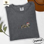 Pepper Comfort Colors T-shirt embroidered with a blue merle Australian Shepherd in a Santa hat trotting with a string of Christmas lights in its mouth