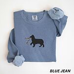 Blue Jean crewneck sweatshirt laid flat with rolled cuffs, embroidered with a black Australian shepherd silhouette carrying a string of Christmas lights