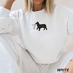 Woman sitting in a White crewneck sweatshirt embroidered with a black Australian shepherd silhouette carrying a string of Christmas lights