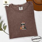 Espresso Comfort Colors T-shirt embroidered with a tricolor Bernese mountain dog puppy in a Santa hat and knit scarf sitting beside a wrapped gift