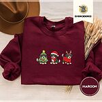 Maroon crewneck sweatshirt with a brown felt hat and dried bunny tail grass, embroidered with three Bernese mountain dog puppies in a Christmas tree costume, a Santa hat with a red scarf and reindeer antlers with a red sweater