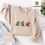 Sand crewneck sweatshirt folded with denim shorts, white sneakers and a potted plant, embroidered with three Bernese mountain dog puppies in a Christmas tree costume, a Santa hat with a red scarf and reindeer antlers with a red sweater