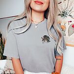 Woman in a Grey T-shirt embroidered with a small tricolor Berner head with its pink tongue out on the left chest
